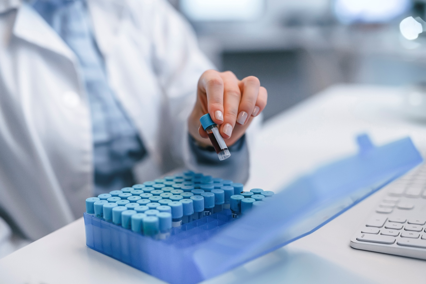 Laboratory manager or technician organizing, sorting, and packing sample vials into a holder working at a lab.